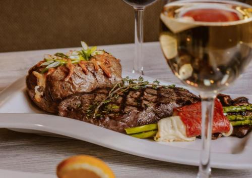 a plate of food with a steak and a glass of wine at Inn on Prince Hotel and Conference Centre Truro in Truro