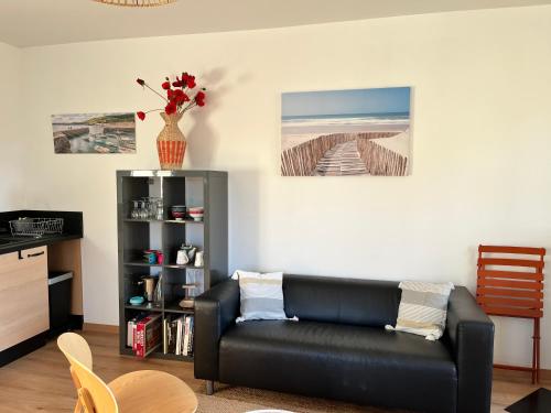 - un salon avec un canapé en cuir noir et une étagère dans l'établissement Maison rénovée à Agon-coutainville proche de la mer, classé meublé de tourisme 3 étoiles, à Agon-Coutainville