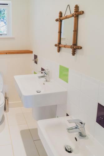 a white bathroom with two sinks and a toilet at Newmarket Gem 5-Bedroom Home with Game Room and Cozy Spaces in Brinkley