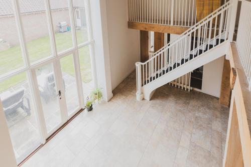 an empty hallway with a staircase and large windows at Newmarket Gem 5-Bedroom Home with Game Room and Cozy Spaces in Brinkley