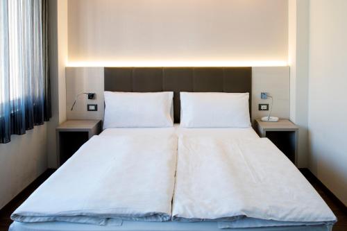 a bedroom with a large white bed with two pillows at Hotel Ariston in Bolzano