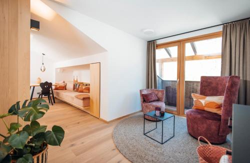 a living room with two chairs and a bed at Neu renovierte Ferienwohnungen im Hotel Hirschentenne in Stams