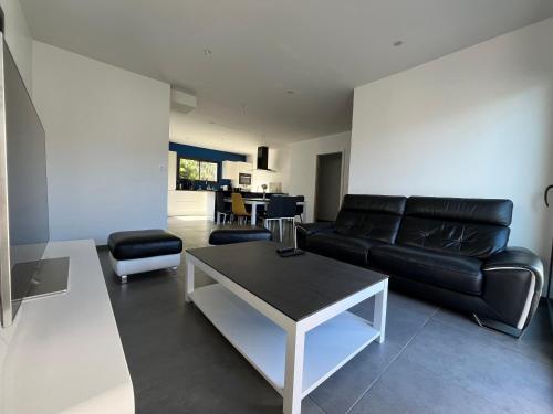 un salon avec un canapé en cuir noir et une table dans l'établissement Maison 4ch/8pers Bourg de Baden, à Baden