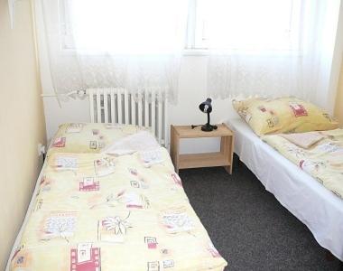 two twin beds in a bedroom with a night stand at Sporthostel Scandinavia in Prague