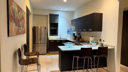 a kitchen with black cabinets and a island with bar stools at Departameto en Residencial La Isla Acapulco Torre G in Acapulco