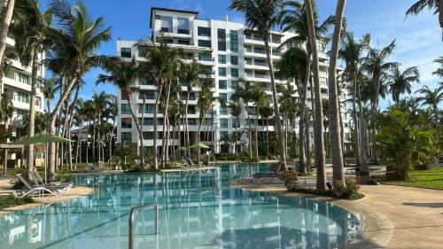 a swimming pool in front of a building with palm trees at Departameto en Residencial La Isla Acapulco Torre G in Acapulco