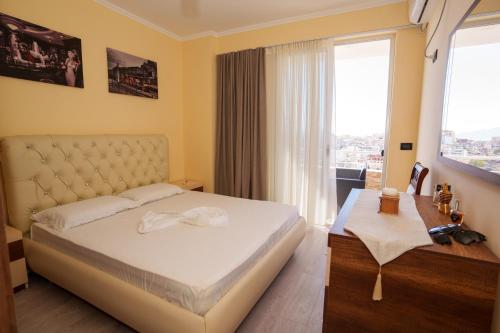 una camera da letto con un letto e una grande finestra di emBrace Apartments a Sarandë