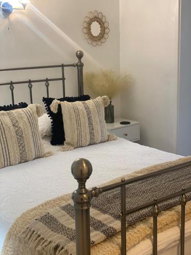Una cama con almohadas blancas y negras y un espejo. en Studio 114, en Isle of Wight