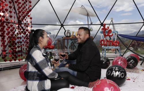 a man and a woman drinking wine in a tent at Amore Mio Glamping in Jenesano