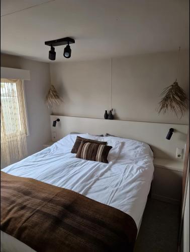 a bedroom with a white bed with a pillow on it at La Casa Di Nyo - Camping De Schatberg in Sevenum