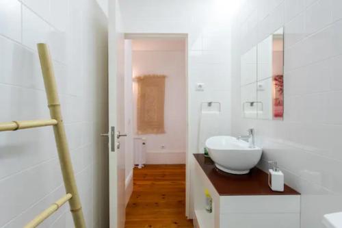 ein weißes Badezimmer mit Waschbecken und Spiegel in der Unterkunft Almada e Fado in Porto
