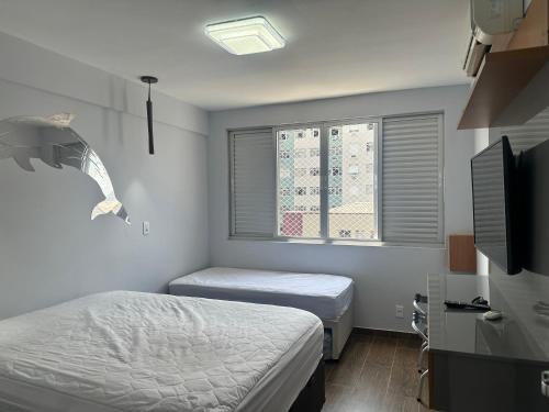 a small bedroom with two beds and a window at Apartamento novo, moderno, completíssimo à beira mar in Santos