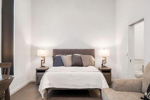 a bedroom with a bed with two lamps and a couch at Grand Suite Pinnacle Brownstones in Rogers