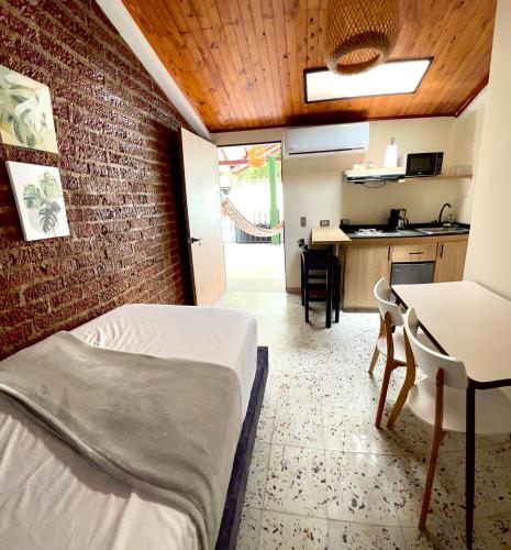 a room with a bed and a table and a kitchen at Magiko Suites in Roldanillo