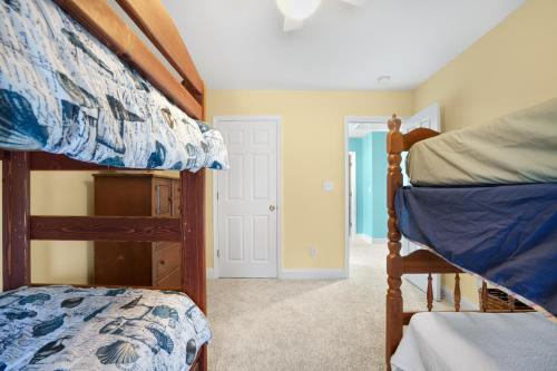 a bedroom with two bunk beds and a hallway at Twins at Bay - Modern luxuries in town! in Cape Charles