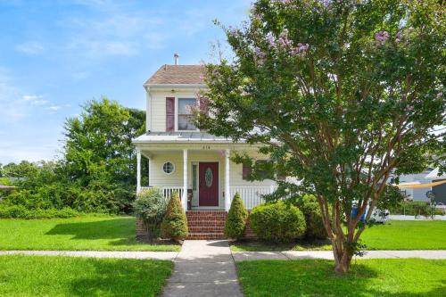 a white house with a red door and a tree at Twins at Bay - Modern luxuries in town! in Cape Charles