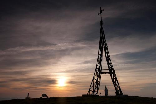 a cross on top of a hill with the sunset at Casa Rural Etxegorri in Orozko