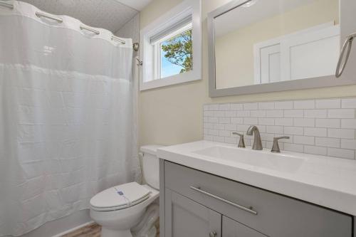 a white bathroom with a toilet and a sink at Wildcat Haven - Waterfront & phenomenal views! in Deep Hole