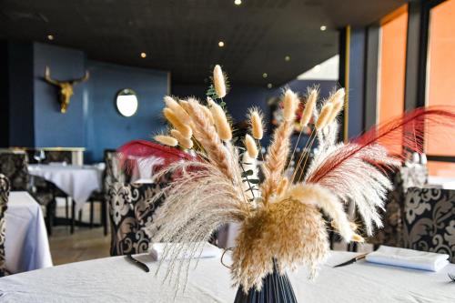a vase with feathers on a table in a restaurant at Arts et Millésimes in Essoyes