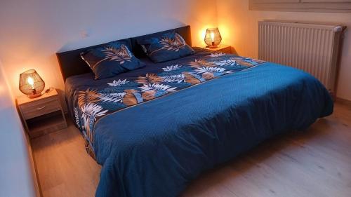 - une chambre avec un lit bleu et deux lampes dans l'établissement L 'oustal de Marguerite, à Saint-Sulpice
