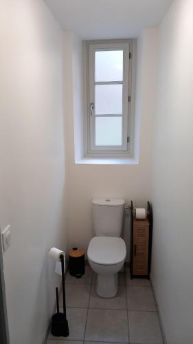 La salle de bains est pourvue de toilettes blanches et d'une fenêtre. dans l'établissement L 'oustal de Marguerite, à Saint-Sulpice