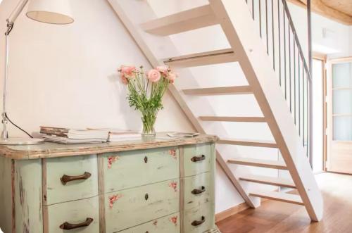 a vase of flowers on a dresser with a staircase at Alla Torre del Barbarossa B&B FORESTERIA in Mandello del Lario