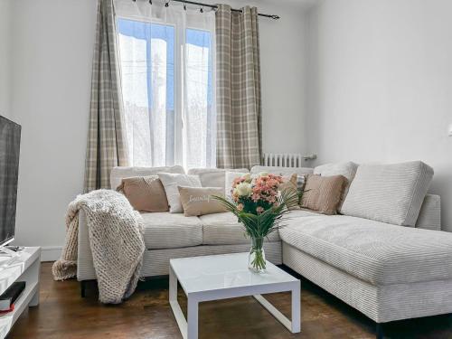 un salon avec un canapé blanc avec un vase de fleurs dans l'établissement Maison Cosy Jardin & Terrasse, à Versailles