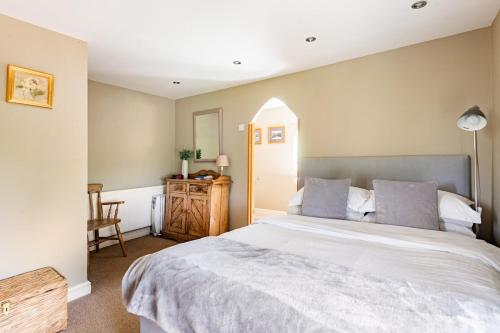 a bedroom with a large bed and a table at Grooms Cottage in Weedon Bec