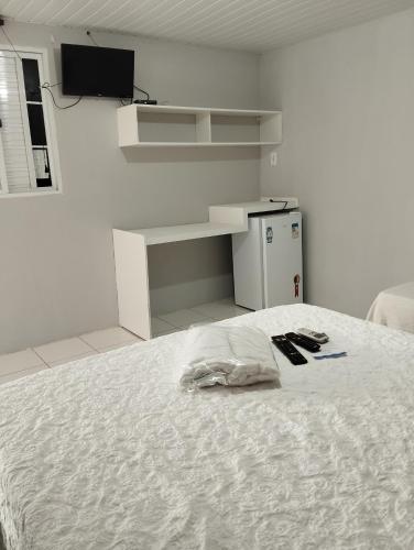 a white room with a bed with two remote controls on it at Ecovila Sertão in Petrolândia
