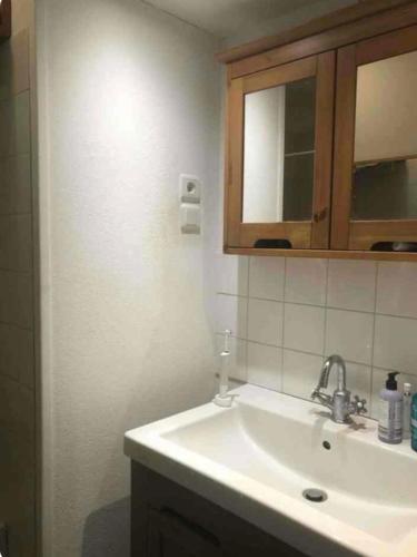 La salle de bains est pourvue d'un lavabo et d'une armoire en bois. dans l'établissement chambre centre ville avec place de parking, à Fougères