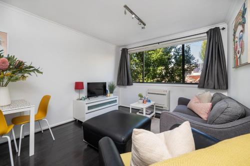 a living room with a couch and a tv at Beach and Track Side Delight in Middle Park in Melbourne