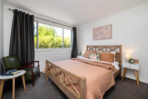 a bedroom with a bed and a chair and a window at Beach and Track Side Delight in Middle Park in Melbourne