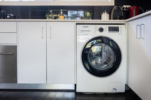 a washing machine in a kitchen with white cabinets at Beach and Track Side Delight in Middle Park in Melbourne