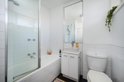 a white bathroom with a tub and a toilet and a shower at Beach and Track Side Delight in Middle Park in Melbourne