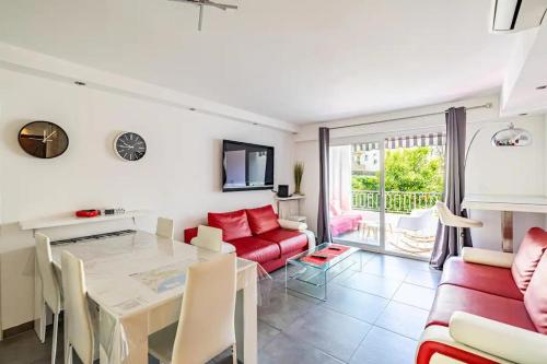 un salon avec une table et un canapé rouge dans l'établissement SUPERBE 3P 2chambres, 2terrasses CANNES centre-ville, 4 min à pied de la Croisette sas-meredith loc, à Cannes