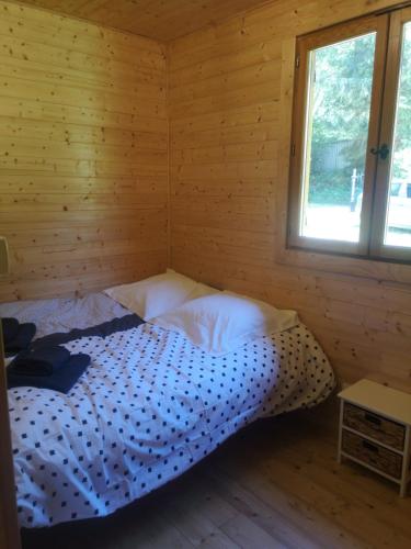 a bed in a log cabin with a window at Au petit bonheur in Le Tholy