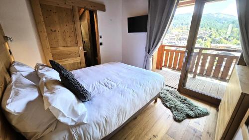 Cette chambre comprend un lit avec des oreillers et un balcon. dans l'établissement Résidence Le Kilimandjaro - Proche centre - Vue sur le village et les montagnes MAE-0941, aux Gets