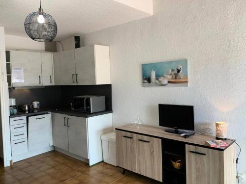 une cuisine avec des armoires blanches et un bureau avec une télévision dans l'établissement Résidence Héliovillage - VILLA 4 pers. CAP D'AGDE MAE-2944, au Cap d'Agde