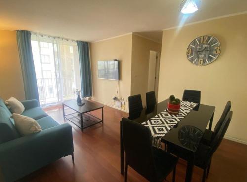a living room with a table and a clock on the wall at Lindo Depto 3 hab y 2 baños in Los Ángeles
