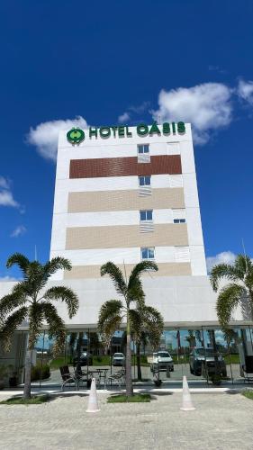 a hotel apartment building with palm trees in front of it at Hotel Oásis de Patos in Patos