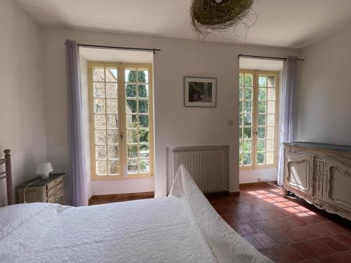 une chambre avec un grand lit et deux fenêtres dans l'établissement Lubéron Gîte Chaleureux 100 m2 piscine jardin, à Saumane-de-Vaucluse
