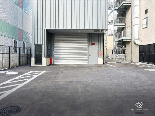 an empty parking lot with a building with a garage at Daiwa Roynet Hotel Akita Ekimae in Akita