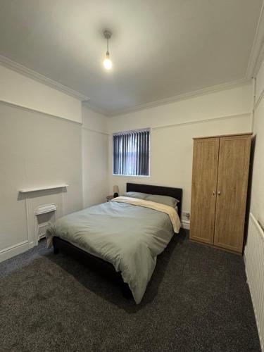 a bedroom with a bed and a wooden cabinet at Serenity Relaxation LTD in Leicester