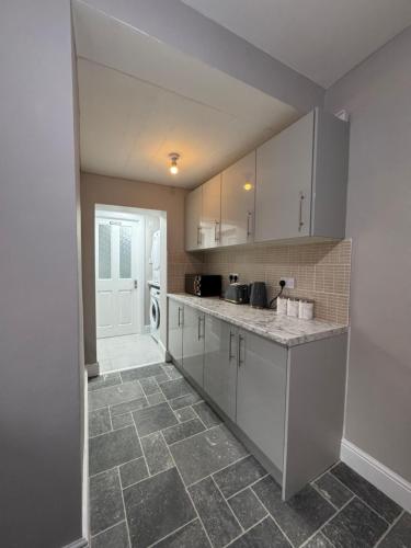 a kitchen with white cabinets and a tile floor at Serenity Relaxation LTD in Leicester