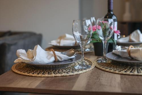 a wooden table with plates and wine glasses on it at 3-Bed Newcastle Home Near Airport & City Centre Free Parking in Kenton
