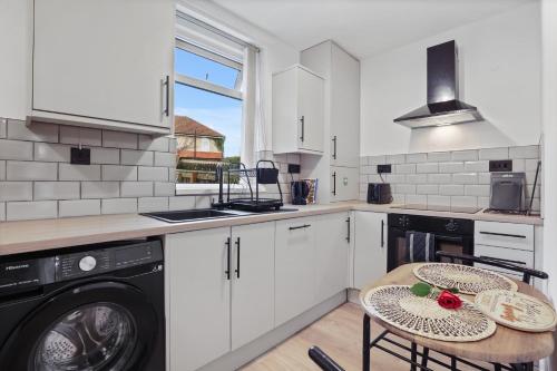 a kitchen with a washing machine and a table with chairs at 3-Bed Newcastle Home Near Airport & City Centre Free Parking in Kenton
