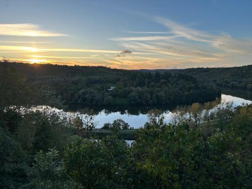 a view of a river with trees and the sunset at La Maison Forestière in Liverdun
