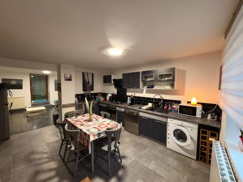 a kitchen with a table with chairs and a washing machine at La Maison Forestière in Liverdun
