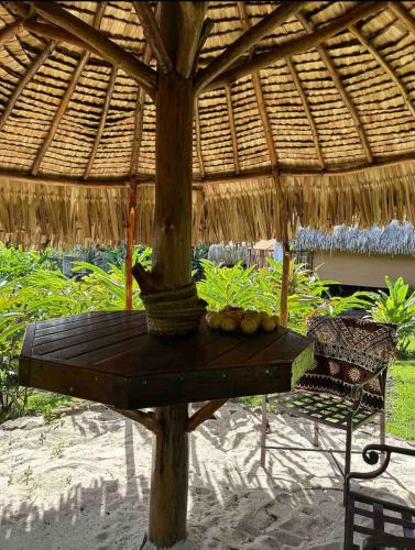 a table under a straw umbrella on the beach at Mererau Lodge in Bora Bora
