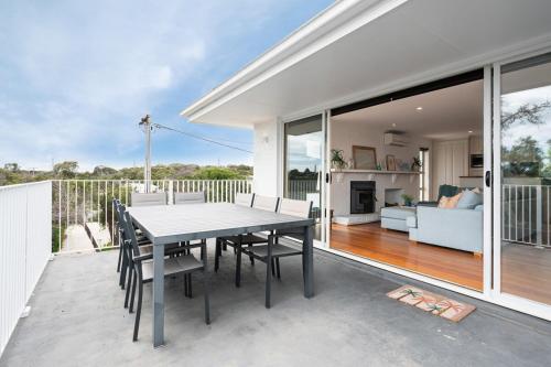 a patio with a table and chairs and a living room at Family Beach Retreat With Heated Pool Blairgowrie in Blairgowrie